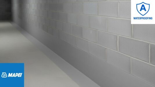 waterproofed-block-wall-with-mapei-planiseal-mr Waterproofed block wall showing Mapei Planiseal MR applied two blocks up from the floor and extending 200 mm onto the concrete floor surface.