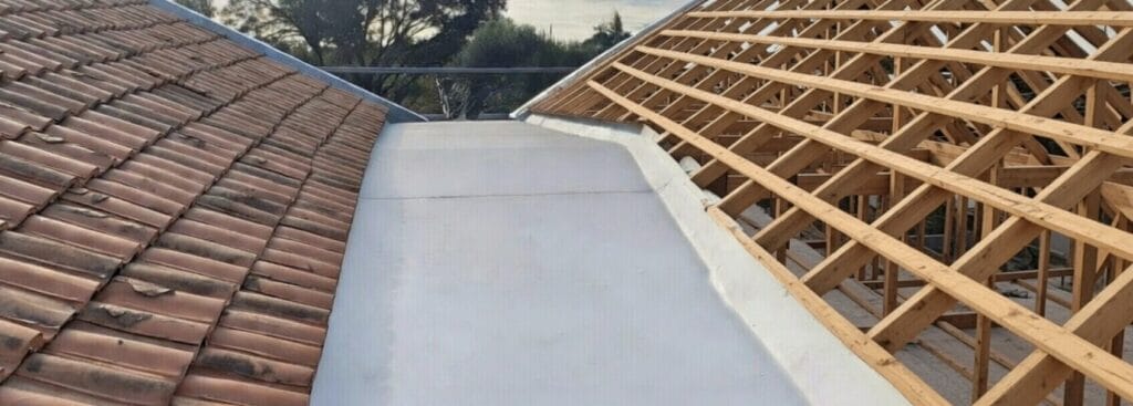 New TPO membrane gutter installed between existing clay tile roof and new timber roof framing on a residential home in Auckland.
